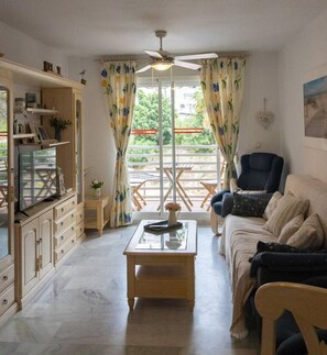 A living room with a sofa, a coffee table, a TV, and a ceiling fan. - Refugio del mar Almuñecar (Almuñécar)