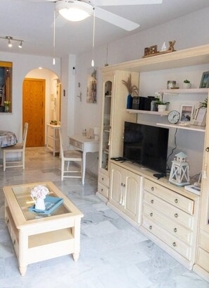 A living room with a TV, a coffee table, and a bookshelf. - Refugio del mar Almuñecar (Almuñécar)