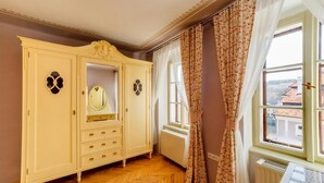 Ein Zimmer mit großem Kleiderschrank, Spiegel und einem mit Vorhängen versehenen Fenster.