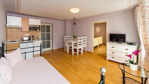 Ein gemütlicher Raum mit Bett, Esstisch, Fernseher und Küchenzeile.