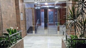 L’entrée d’un hôtel au design moderne, avec une porte d’entrée en verre, une enseigne au-dessus de la porte et des plantes en pot de chaque côté.