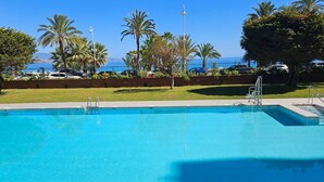Une piscine offrant une vue dégagée sur la mer et les palmiers en arrière-plan.