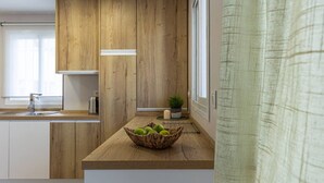 Een moderne keuken met houten kastjes, een spoelbak en een aanrecht met een fruitmand.