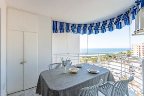 Varanda com mesa posta para dois, com vista para a praia.
