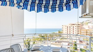 Een balkon met een tafel voor twee, met uitzicht op een strand en de skyline van de stad.