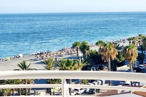 Uma praia com palmeiras, guarda-sóis e pessoas.