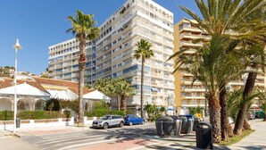 Een meerlaags hotel met balkons, palmbomen en een helderblauwe lucht.