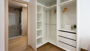 A walk-in closet with open shelving, a hanging rod, and a small shelf with folded towels. - Esencia Marina la Najarra (Almuñécar)