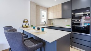 A modern kitchen with a central island, built-in appliances, and a seating area with chairs. - Esencia Marina la Najarra (Almuñécar)