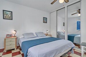 Une chambre à coucher avec un lit, des tables de chevet, une radio et un miroir.