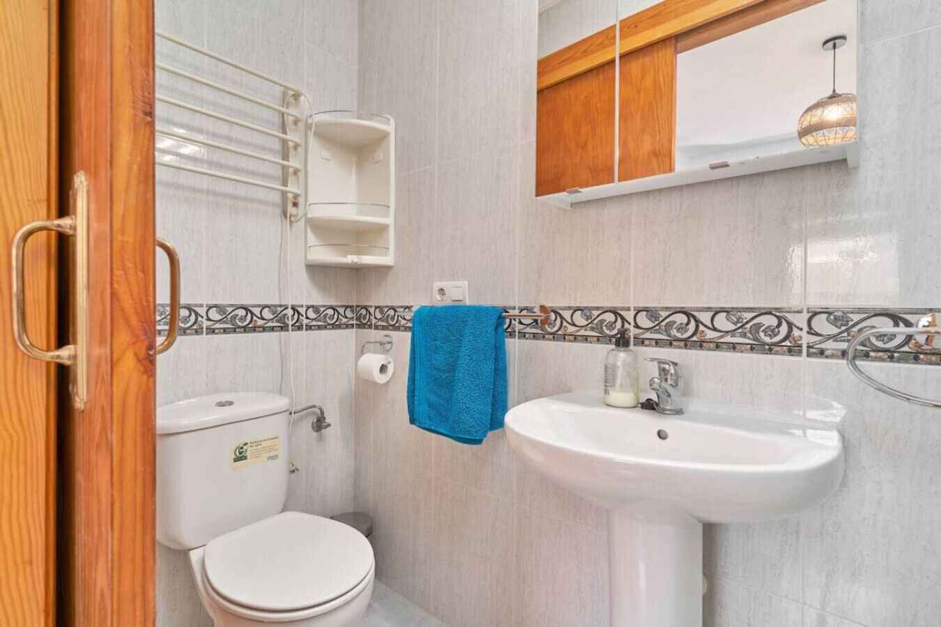 A bathroom with a toilet, sink, and a towel hanging on the wall.