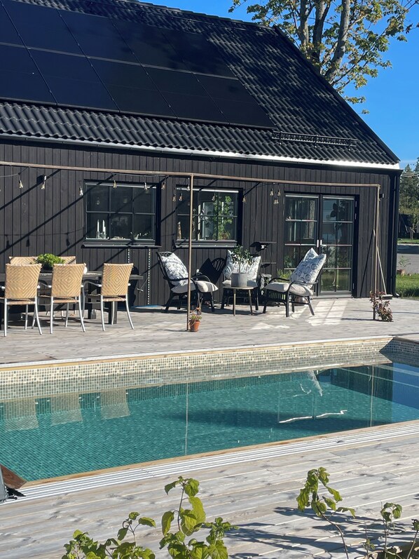 A modern building with a pool, outdoor seating, and large windows. - Villa Golfgatan 32 Vintrosa (Vintrosa)