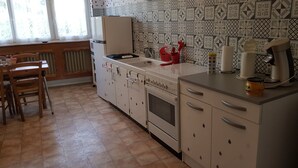A kitchen with a stove, oven, and a dining area with a chair and table.