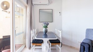 Et spiseområde med et bord, stole, en vase med blomster og en skydedør i glas.
