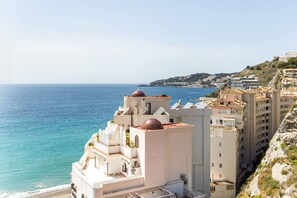 Um edifício costeiro com vista para o mar, com várias varandas e uma cúpula imponente.