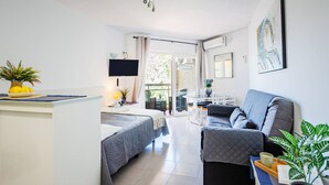 Et moderne hotelværelse med seng, sofa, fjernsyn og balkon med bord og stole.