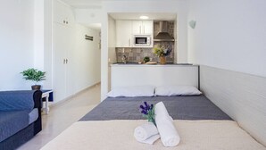 Et kompakt soveværelse med seng, sengebord og en lille potteplante.
