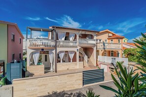 A two-story residential building with balconies, a gated entrance, and a clear blue sky. - Apartment Sinanovic 2 (Vir)