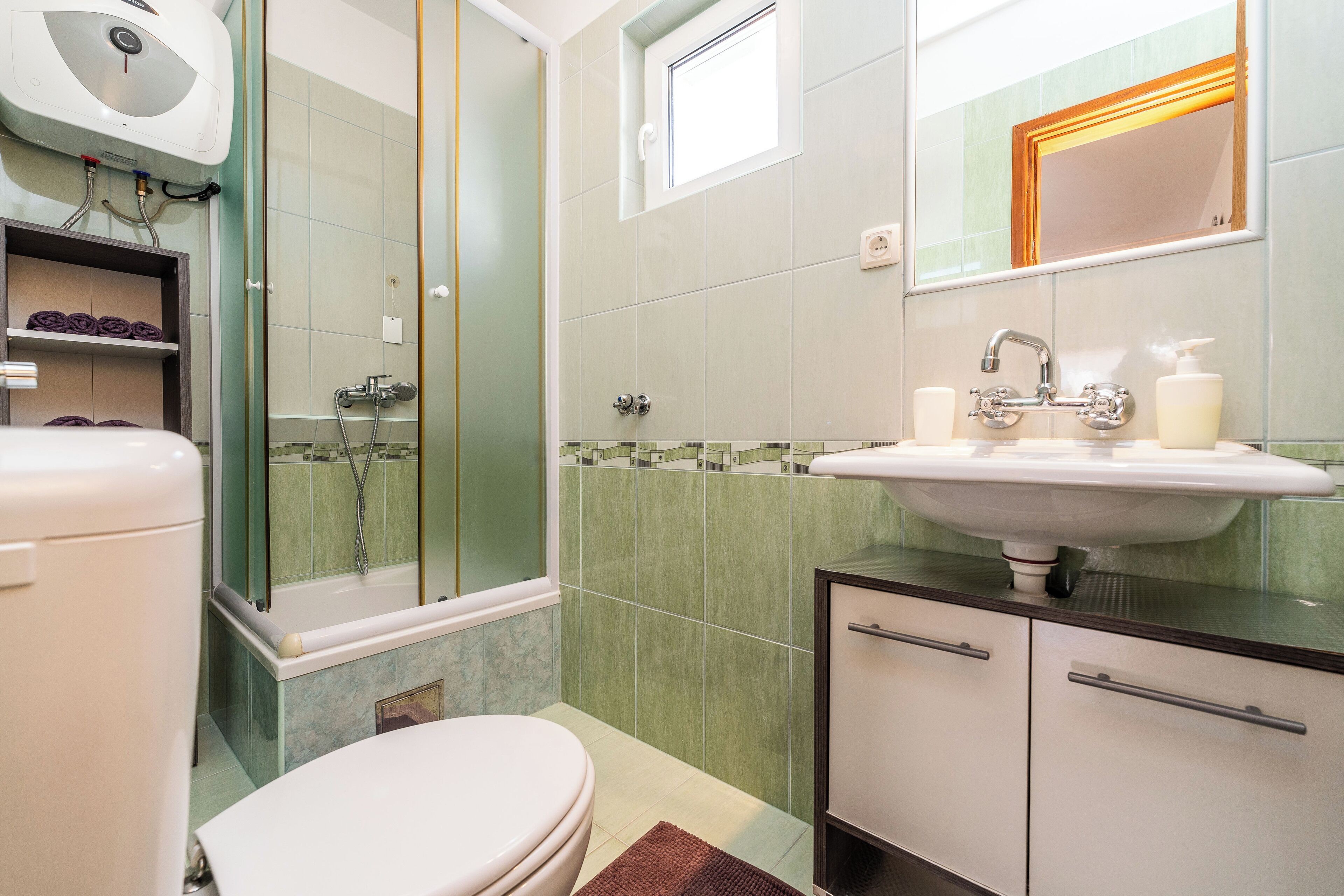Une salle de bain comprenant des toilettes, un lavabo, une douche et une petite fenêtre.