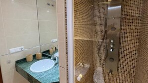 A bathroom with a sink, mirror, and shower enclosure.