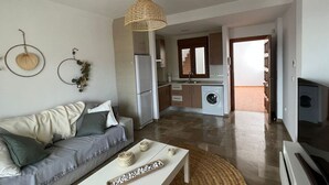 A modern apartment with a living room, kitchenette, and laundry area.