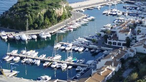 Ein Yachthafen mit vertäuten Booten, eine kleine Insel und Gebäude entlang der Uferlinie.