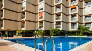 A swimming pool with metal railings, surrounded by a tiled deck. - Nice seafront apartment (Almuñécar)