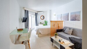 A modern hotel room with a bed, a sofa, a desk, and a TV. - Nice seafront apartment (Almuñécar)