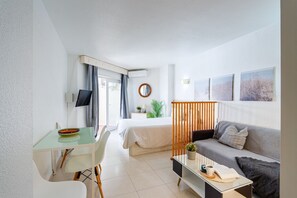 A modern hotel room with a bed, a sofa, a desk, and a TV. - Nice seafront apartment (Almuñécar)