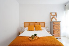 A bedroom with a bed, two nightstands, a dresser, and a window with curtains.