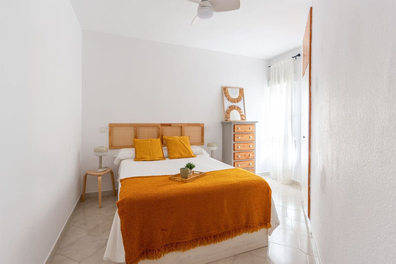 Une chambre à coucher comprenant un lit, des tables de chevet, une commode et un ventilateur de plafond.