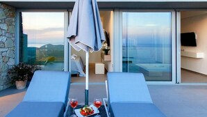 Un espace extérieur moderne, aménagé avec une table, deux fauteuils et un balcon vitré offrant une vue sur la mer.