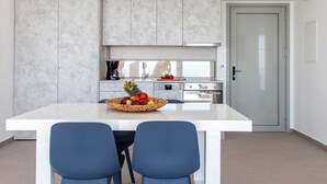 Une cuisine moderne avec un îlot central, deux chaises bleues et un panier de fruits.