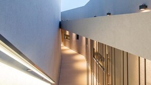 Un couloir au design architectural moderne, caractérisé par un plafond incliné et une série de luminaires fixés au mur.