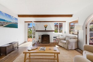 Ein Wohnzimmer mit Kamin, einer Couch, einem Couchtisch und einem Fernseher, der 'SAN DIEGO' zeigt.