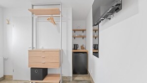 A compact kitchen with a built-in dishwasher, a wooden cabinet, and a wall-mounted TV. - RICLS Apartmenthaus - BRIGHT Collection (Wurmberg)