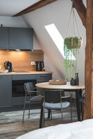 Una cocina moderna con armarios grises, una mesa redonda de madera y plantas colgantes.