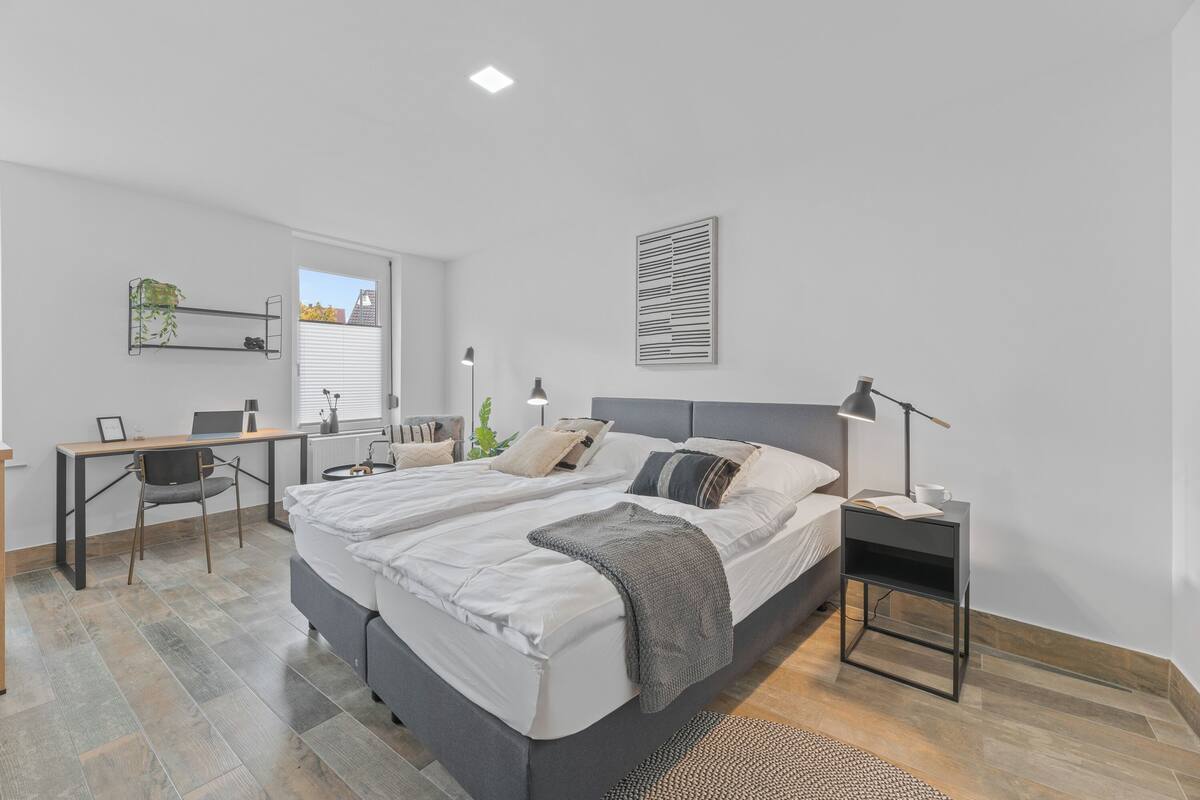 A modern bedroom with a large bed, a desk, and a chair.