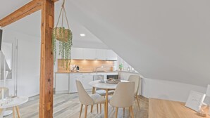 A modern kitchen with white cabinets, a wooden dining table, and chairs. - RICLS Apartmenthaus - BRIGHT Collection (Wurmberg)