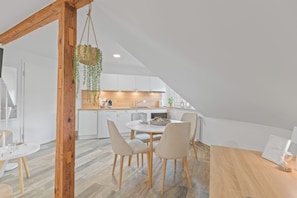 A modern kitchen with white cabinets, a wooden dining table, and chairs. - RICLS Apartmenthaus - BRIGHT Collection (Wurmberg)