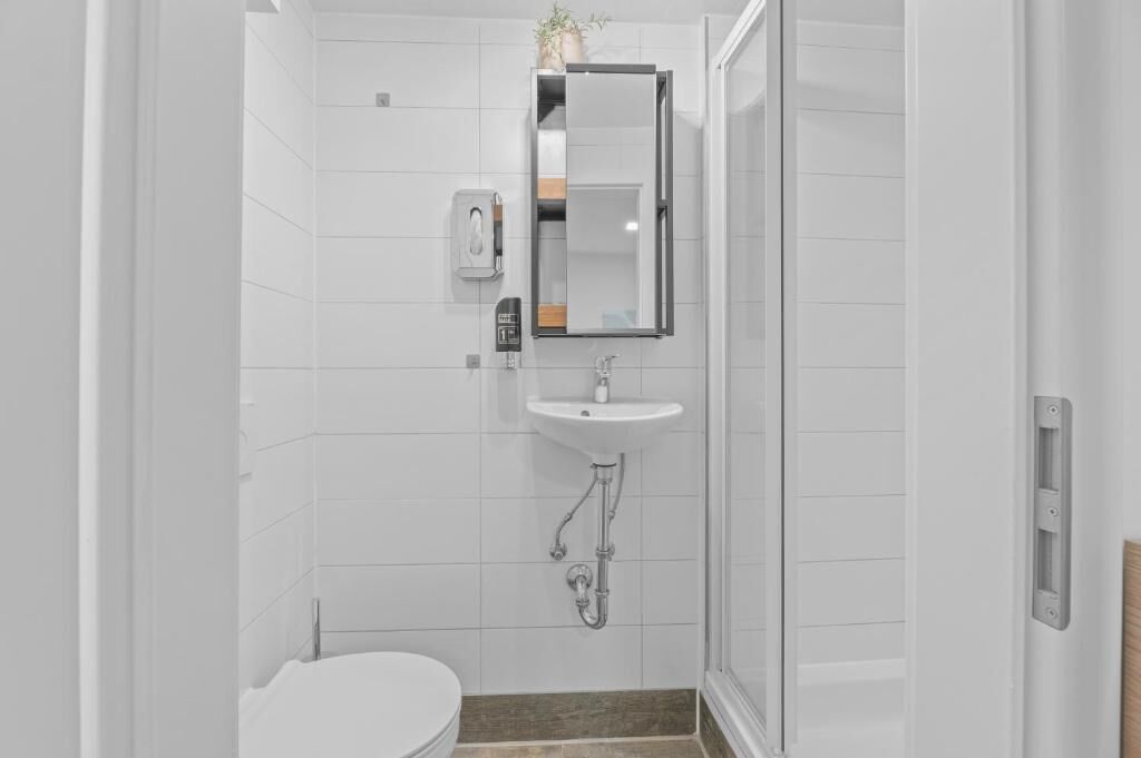 A bathroom with a white sink, mirror, and toilet.