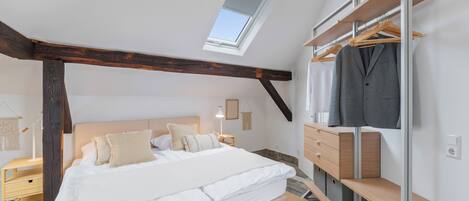 Un dormitorio con tragaluz, una cama, un armario y una mesita de noche.