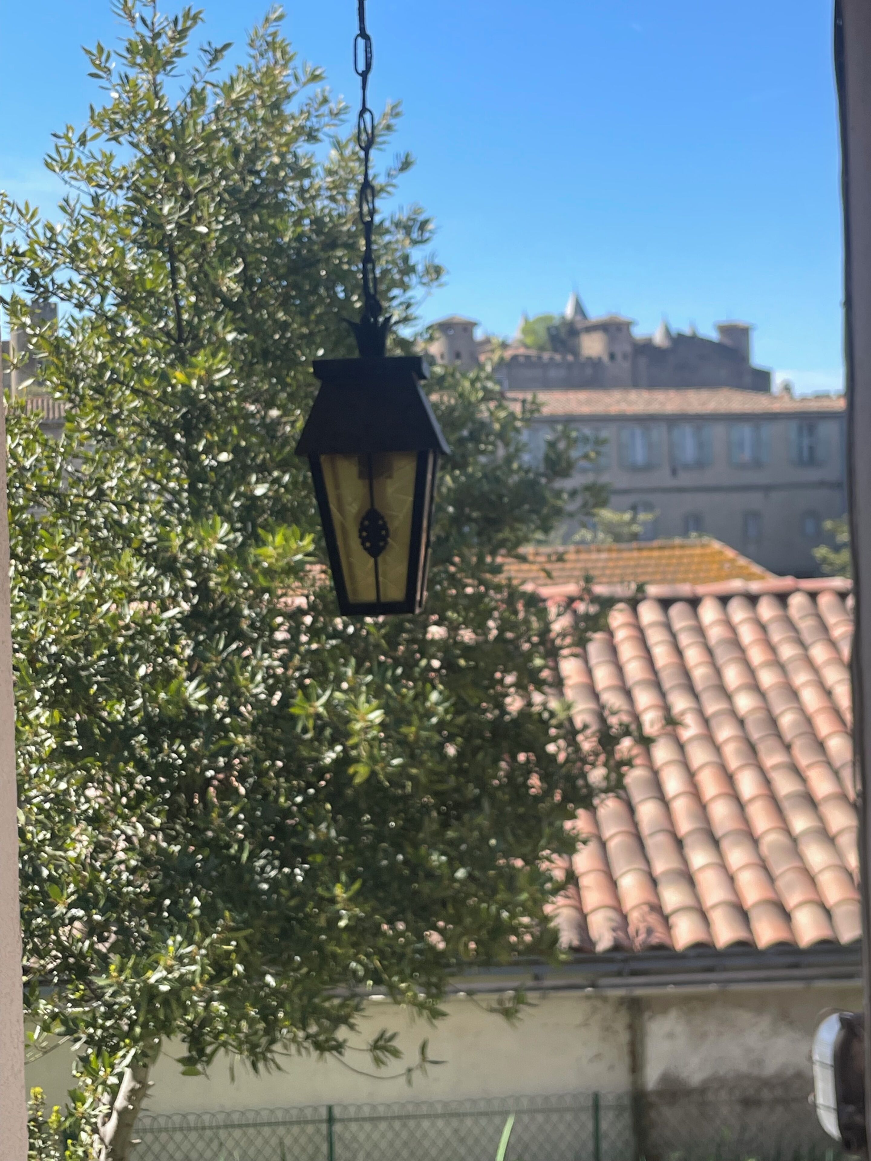 Une lanterne suspendue, un arbre et un bâtiment avec un toit en tuiles.