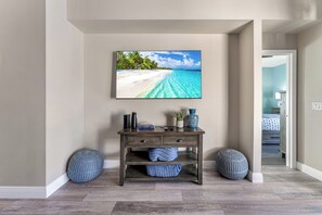 Ein Zimmer mit einem Holzkonsolentisch, einem gerahmten Foto vom Strand und zwei runden Hocker.