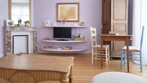 A living room with a fireplace, television, wooden table, and chairs. - Charming house near the beach for 6 people (Les Sables-d´Olonne)