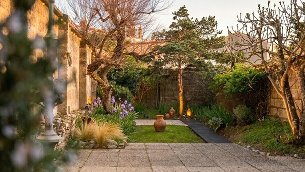 A garden with a paved walkway, potted plants, and a rustic stone wall. - Charming house near the beach for 6 people (Les Sables-d´Olonne)