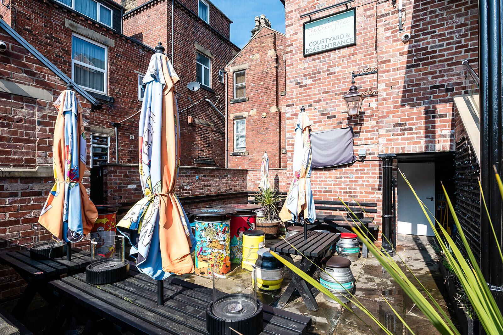 Un patio con mesas al aire libre, sombrillas y macetas con plantas.