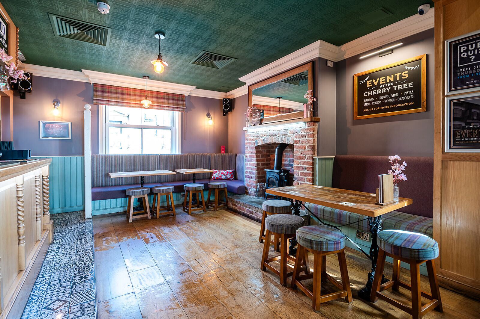 A cozy restaurant with a brick fireplace, wooden bar stools, and a seating area with a view of the street.