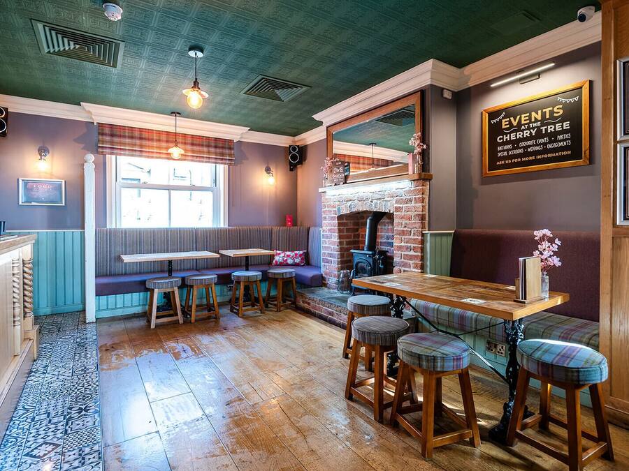 A cozy restaurant with a brick fireplace, wooden bar stools, and a seating area with a view of the street.