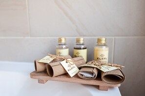 A wooden shelf with rolled-up towels and bottles of ELSYL shower cap. - Cherry Tree Inn  (Horbury)